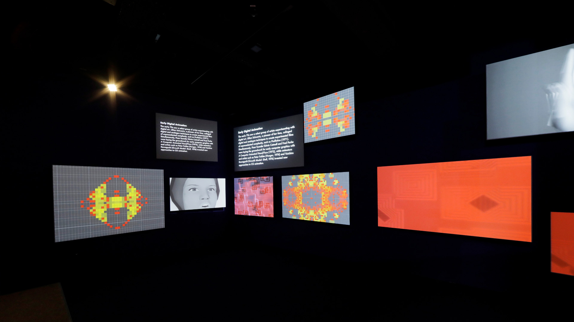 Vor schwarzem Hintergrund leuchten mehrere Bildschirme, die verschiedene Ausstellungsobjekte darstellen.