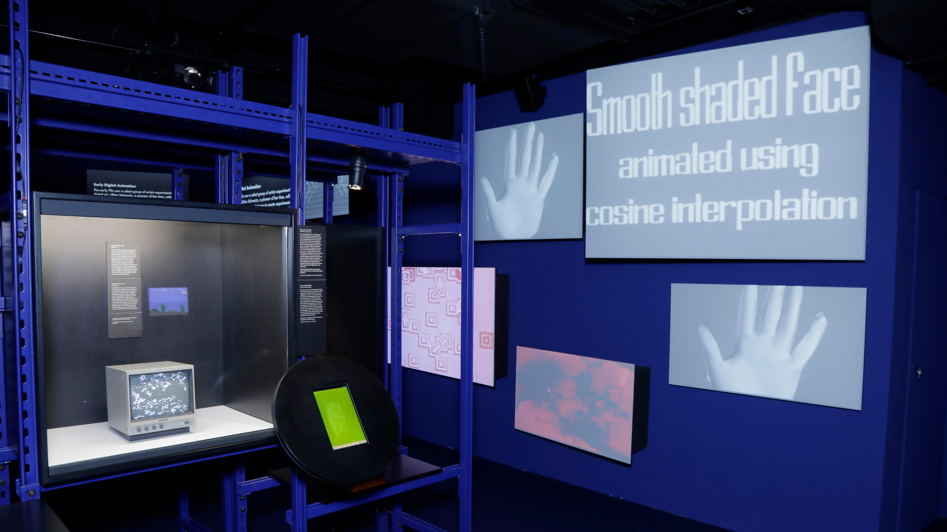 Ein Blick in die Ausstellung zeigt, in einer blauen Umgebung verschiedene Objekte an einer Wand und einer Vitrine.