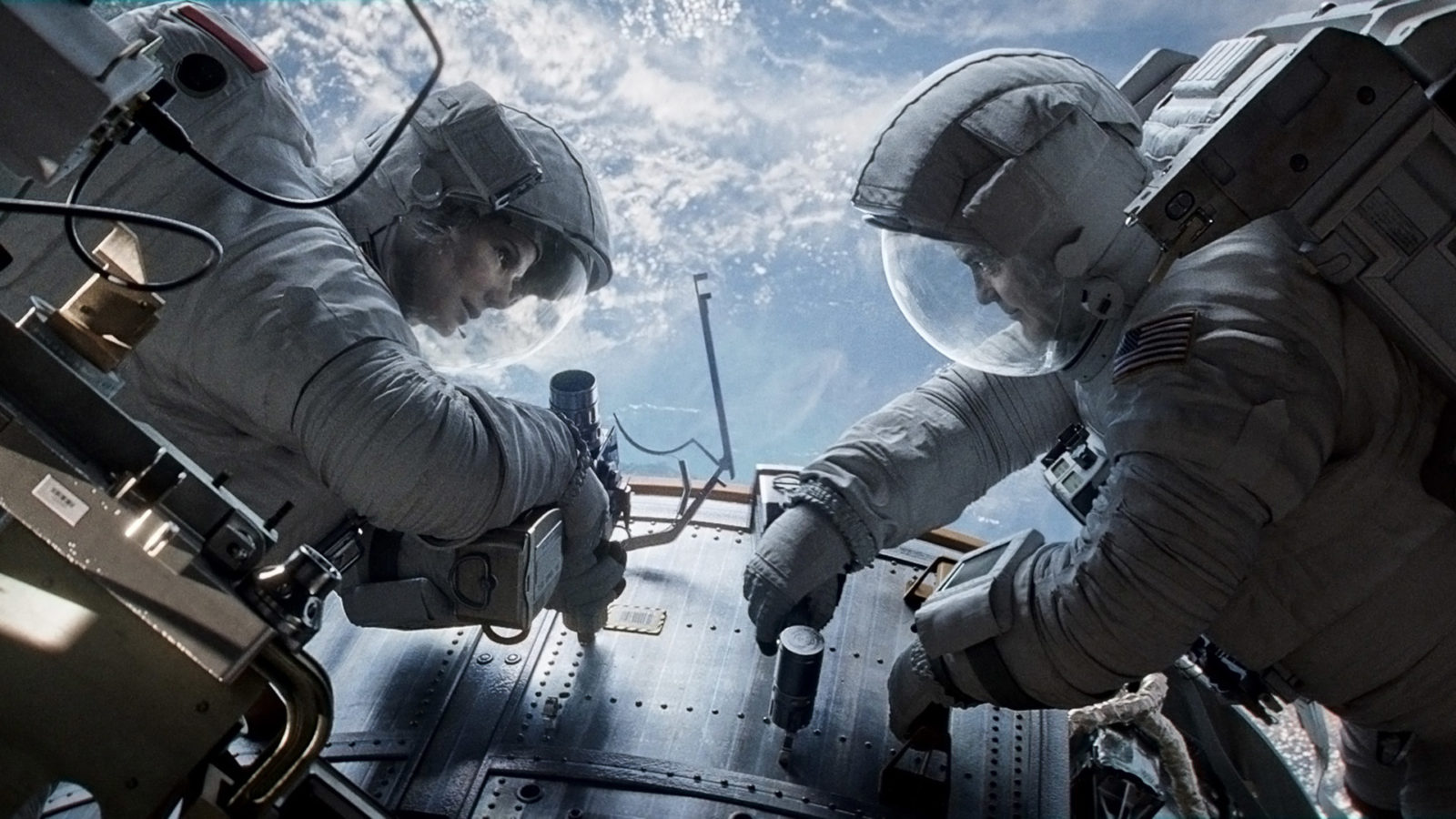 Filmstill aus dem Film: Gravity. Zwei Astronauten benutzen Werkzeuge.