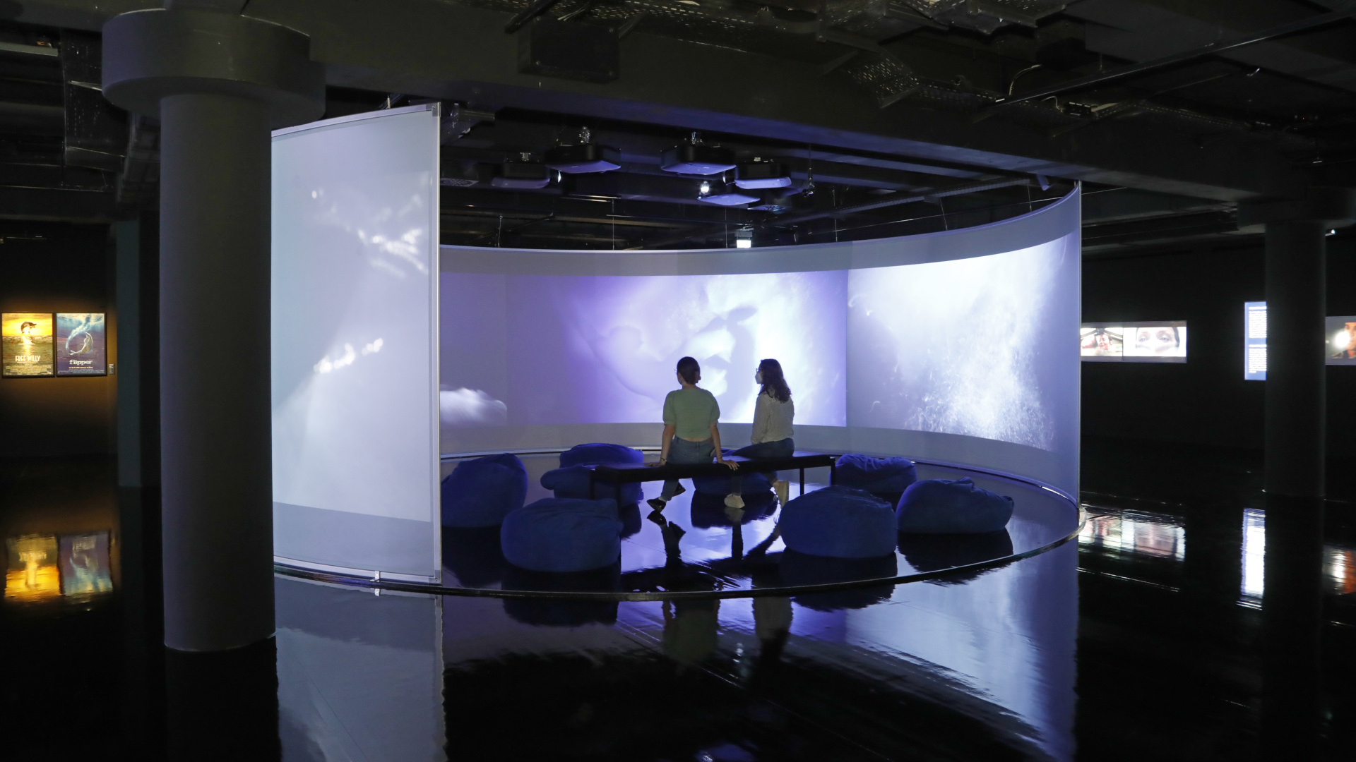 zwei Personen sitzen im zentralen Projektionsraum der Ausstellung IM TIEFENRAUSCH