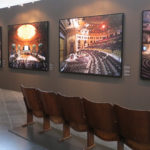 Ausstellungsansicht: Eine Reihe Kinosessel vor einer Wand mit gerahmten Fotografien