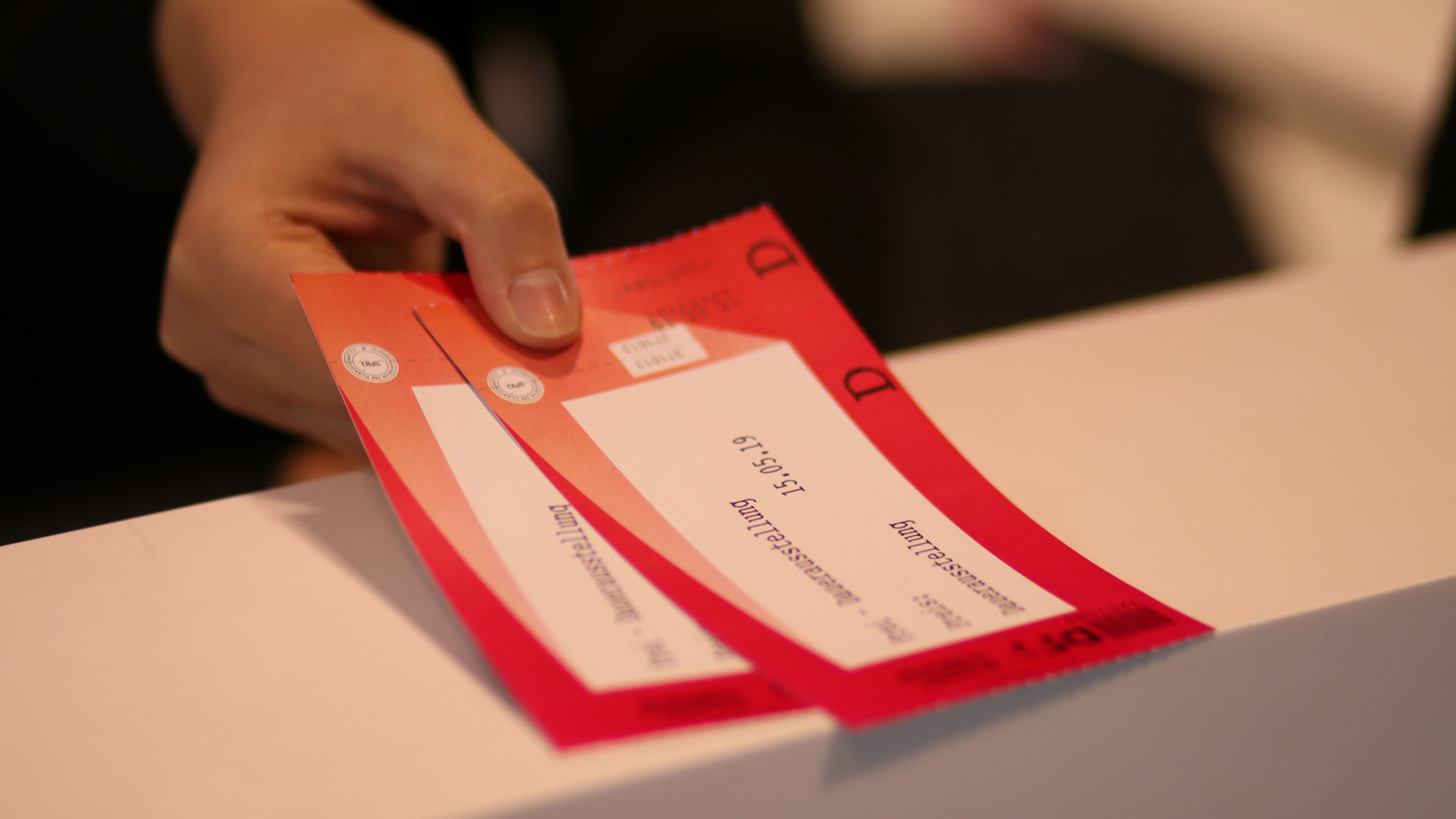 Zwei rote Tickets werden von jemanden über den Tresen gereicht.