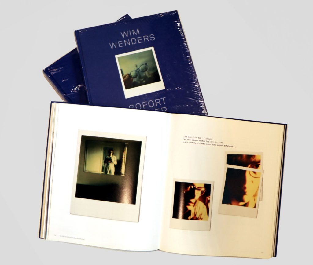 Ein aufgeklapptes Fotobuch liegt auf einem Stapel blau eingebundener weiteren Fotobüchern.