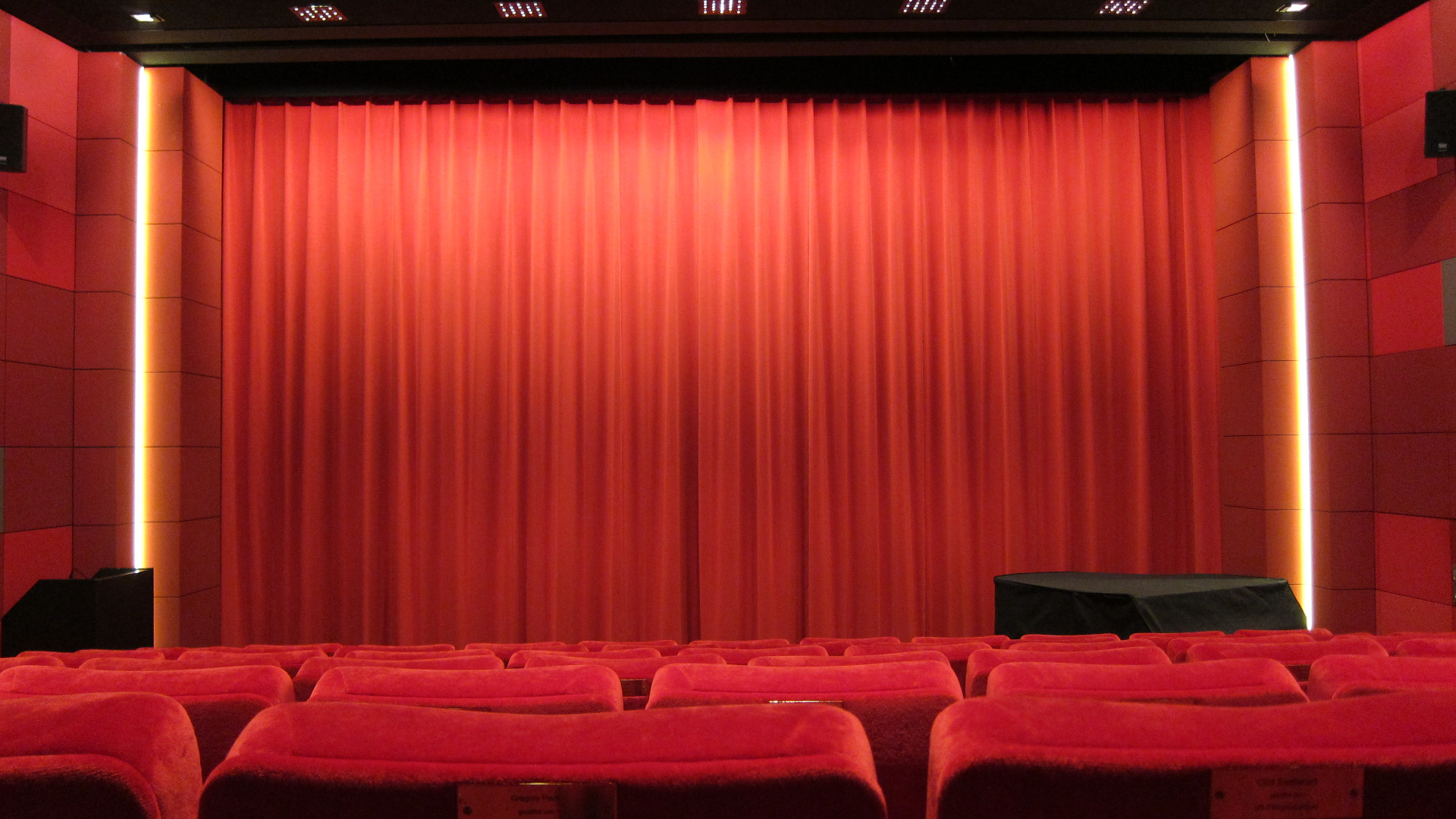 Der rote Vorhang im Kino des DFF ist schwach Beleuchter und einige rote Samtsessel sind zu sehen.