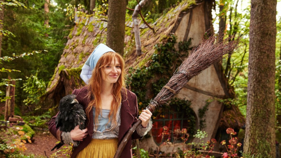 Filmstill Karoline Herfurt als die kleine Hexe vor ihrem windschiefen Haus im Wald mit Besen in der Hand
