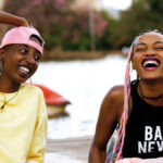 Filmstill RAFIKI Samantha Mugatsia, Sheila Munyiva sitzen zusammen an einem See und lachen