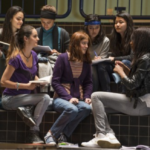 Gruppe Schülerinnen sitzen in LES HÉRITIERS in einem Schulflur zusammen