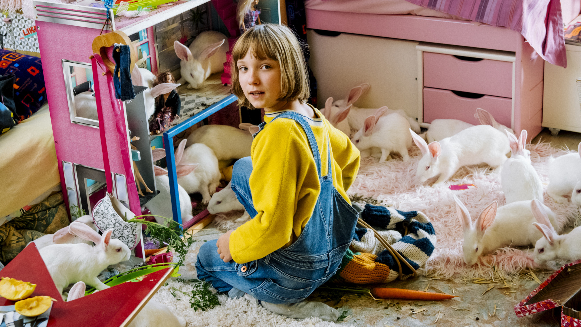 Filmstill aus Mein Lotta-Leben. Ein Mädchen sitzt auf dem Teppich ihres Kinderzimmers und spielt mit ihrem Puppenhaus.