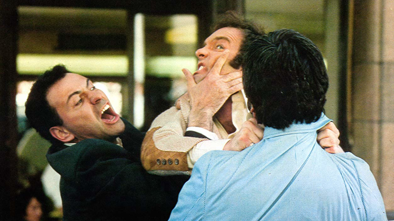 Filmstill, das drei sich streitende Männer zeigt, die gerade handgreiflich werden.
