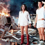 Angelina Jolie und Brad Pitt schauen erschrocken während sie vor einem brennenden Trümmerfeld stehen