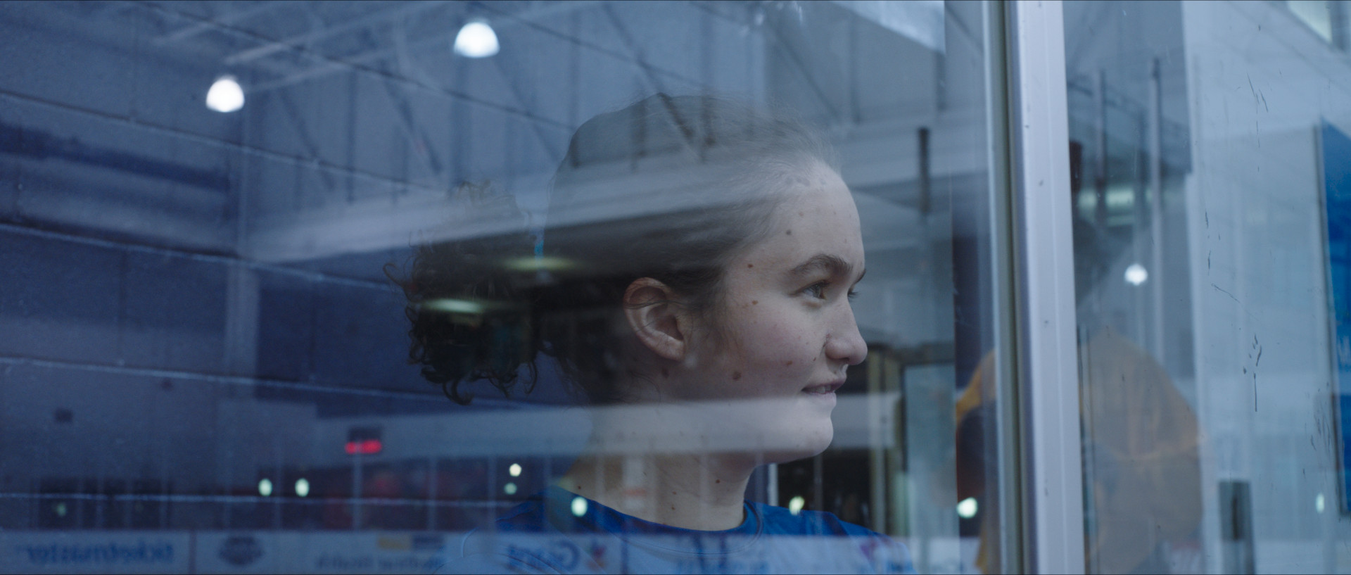 Filmstill aus The Reason I Jump. Ein Mädchen steht hinter einer Fensterscheibe.
