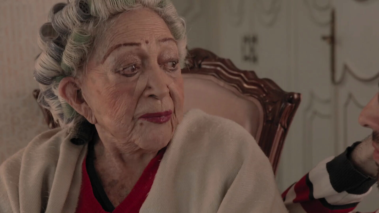 Filmblick aus Mamacita. Eine alte Frau ist im Sitzen zu sehen.
