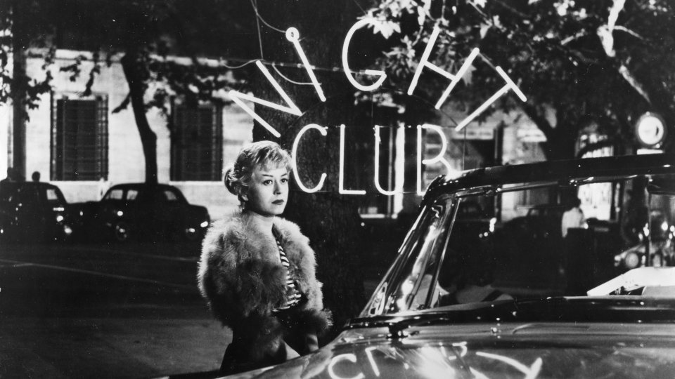 Filmstill aus dem Schwarz-Weiß-Film Die Nächte der Cabiria. Eine junge Frau steht an einem Auto.