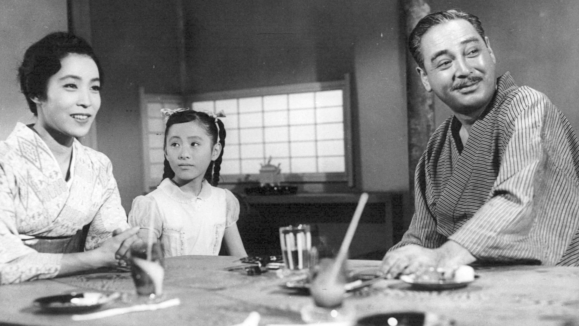 Filmstill aus Aki Tachinu. Eine Frau und ein Mann im Kimono sitzen mit einem Mädchen am Tisch.