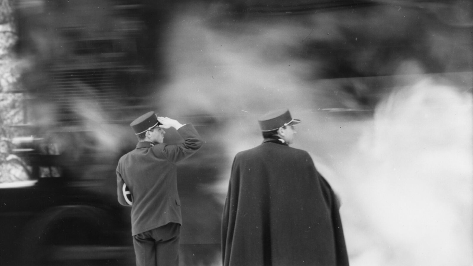 Filmstill aus Liebe nach Fahrplan. Zwei Männer mit Schirmmütze stehen im Nebel einer Lokomotive.