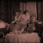 Filmstill aus LOLA MONTEZ, DIE TÄNZERIN DES KÖNIGS: Ein Mann sitzt an einem Tisch, eine Frau sitzt auf seiner Armlehne und blickt ihm über die Schulter