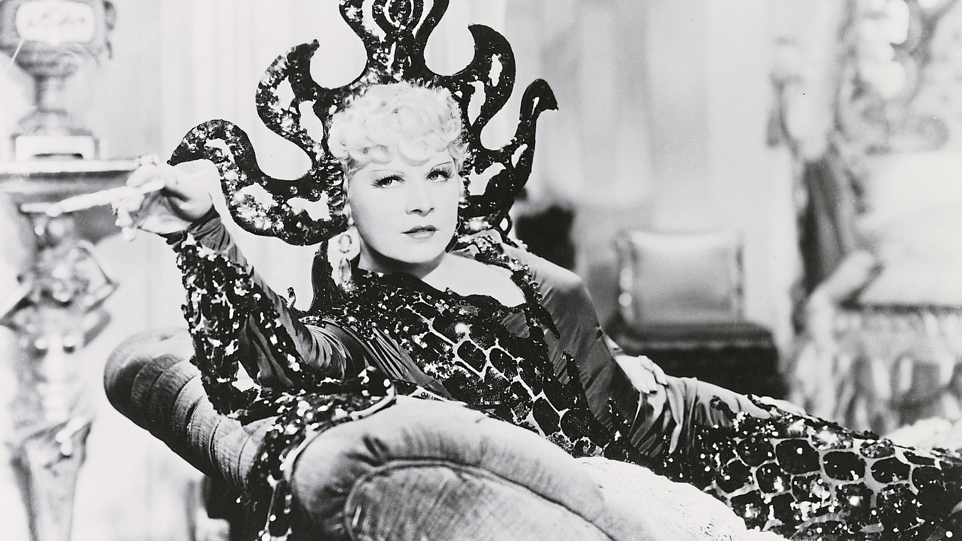 Film still from "Klondike Annie" showing Mae West sitting Mae West on a canapé