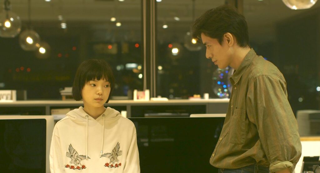 Ein junges japanisches Paar in einem Büro, beide schauen traurig bis ernst