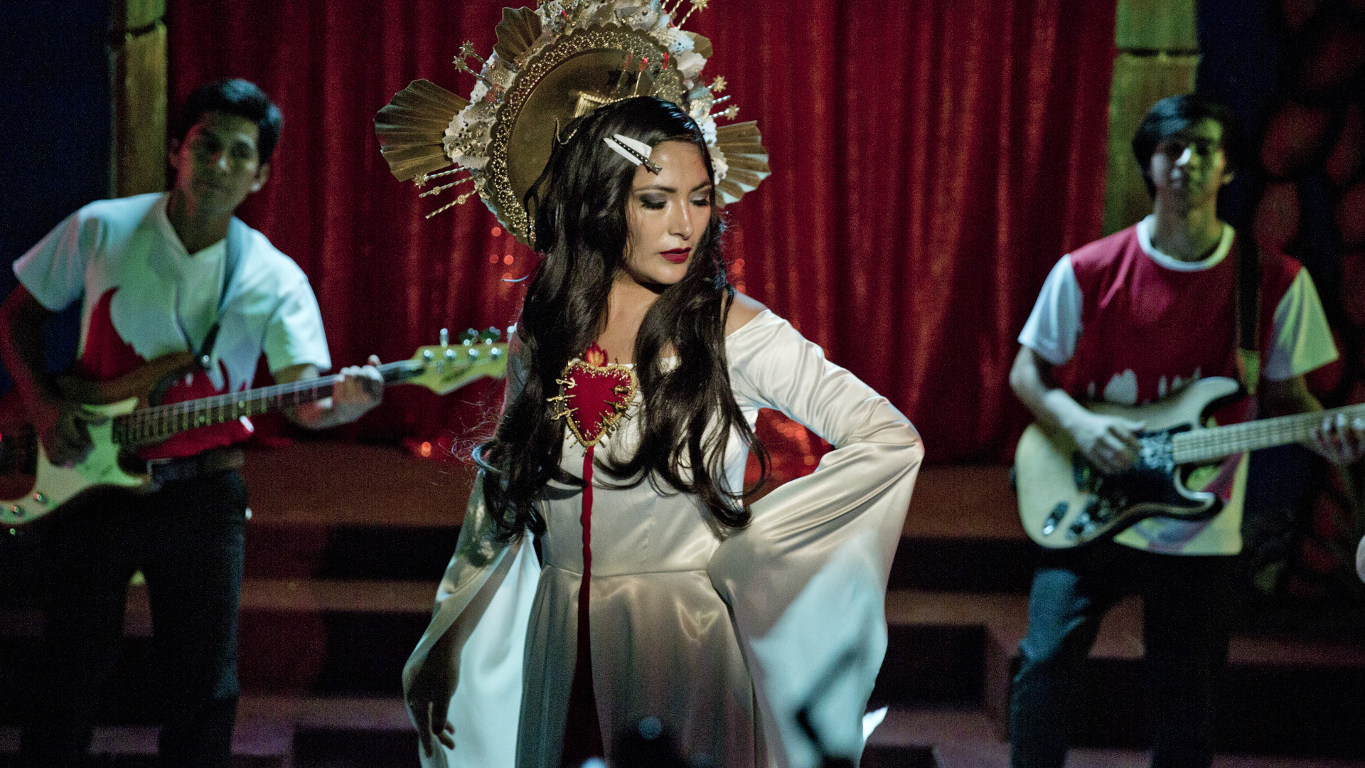 Filmstill aus Lina de Lima: Eine Frau auf einer Bühne, im Hintergrund zwei Gitarristen