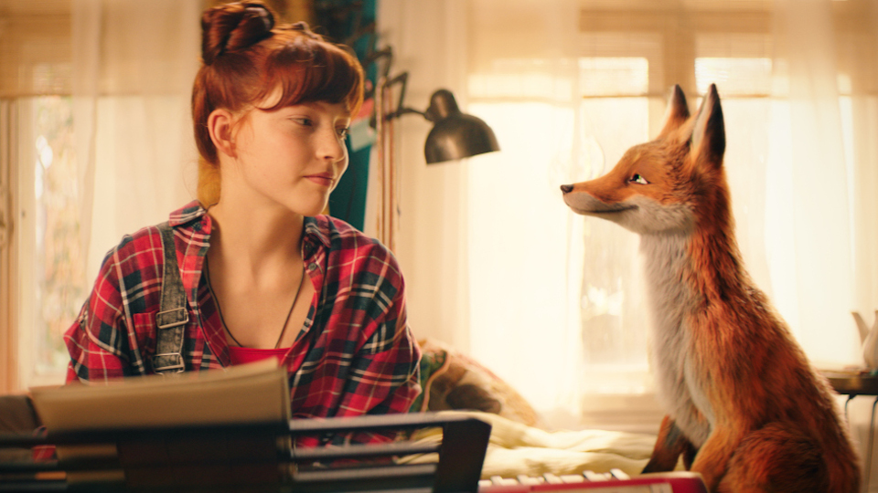 Filmstill aus Die Schule der magischen Tiere 2: Ein Mädchen und ein Fuchs sitzen sich gegenüber und lächeln einander an