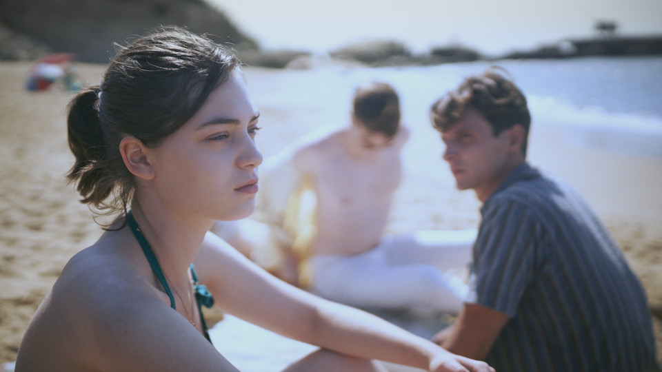 Filmstill aus Das Ereignis: Eine Frau sitzt am Strand und blickt in die Ferne