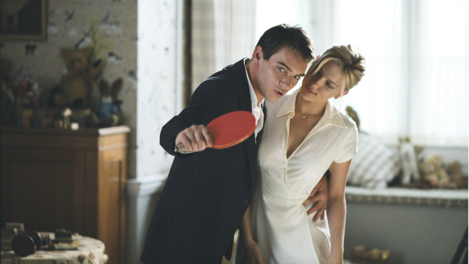 Filmstill aus Match Point: Ein Mann mit einem Tischtennisschläger legt einen Arm um eine Frau