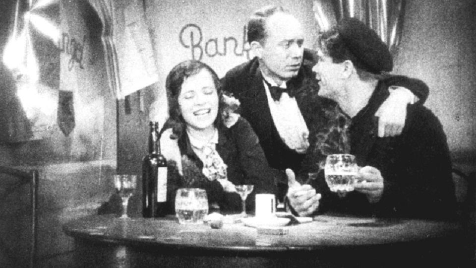 Filmstill aus Razzia in St. Pauli: Drei Personen sitzen mit Getränken an einem Tisch
