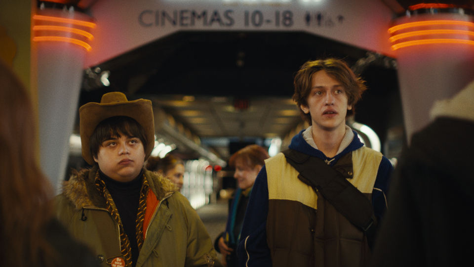 Filmstill aus I Like Movies: Zwei Jungen stehen vor einem Kino