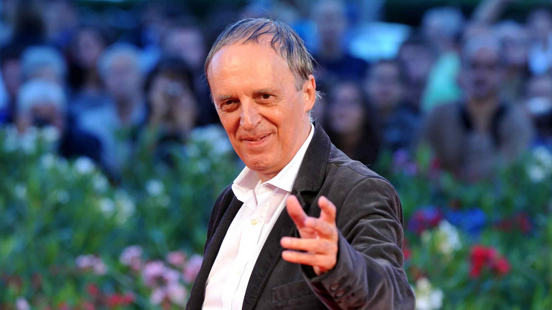 Photo of Dario Argento in a suit at the Venice Film Festival in 2010 with the audience in the background (blurry)