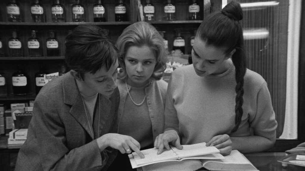 Drei Frauen Mitte der 1960 er Jahre in einer Apotheke über ein Buch gebeugt