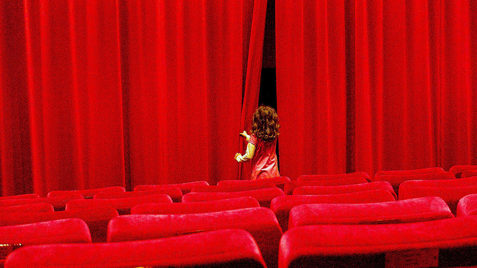 Kind schaut hinter den roten Vorhang des Kinos des DFF