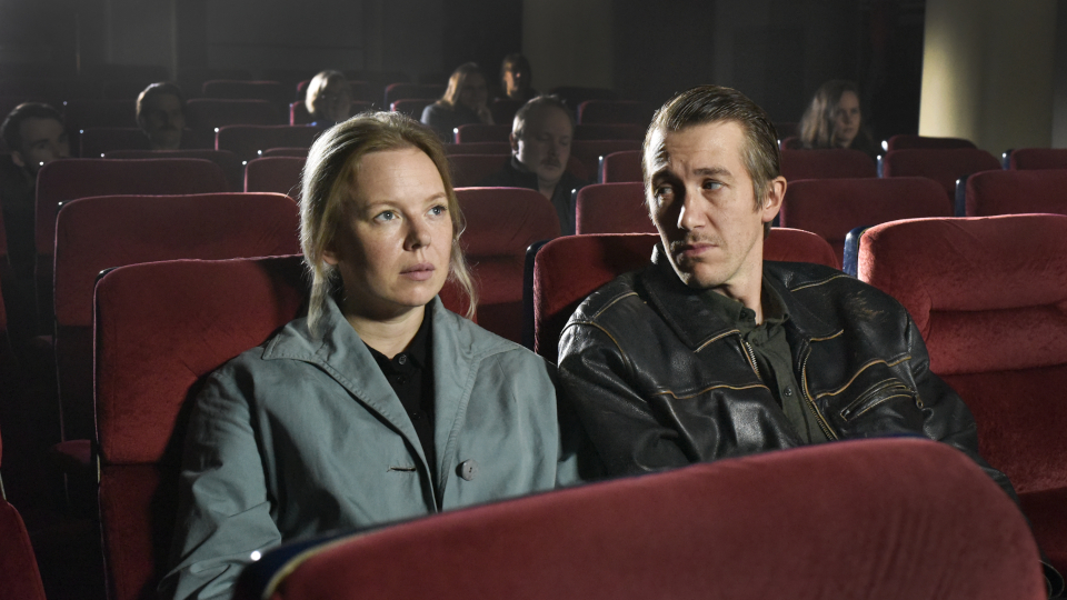 Filmstill aus Fallende Blätter: Eine Frau und ein Mann sitzen im Kino, der Mann blickt die Frau an