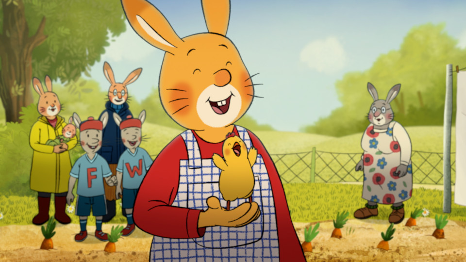 Filmstill aus Karlchen - Das große Geburtstagsabenteuer: Ein Hase hält ein Küken in der Hand, im Hintergrund eine Hasenfamilie